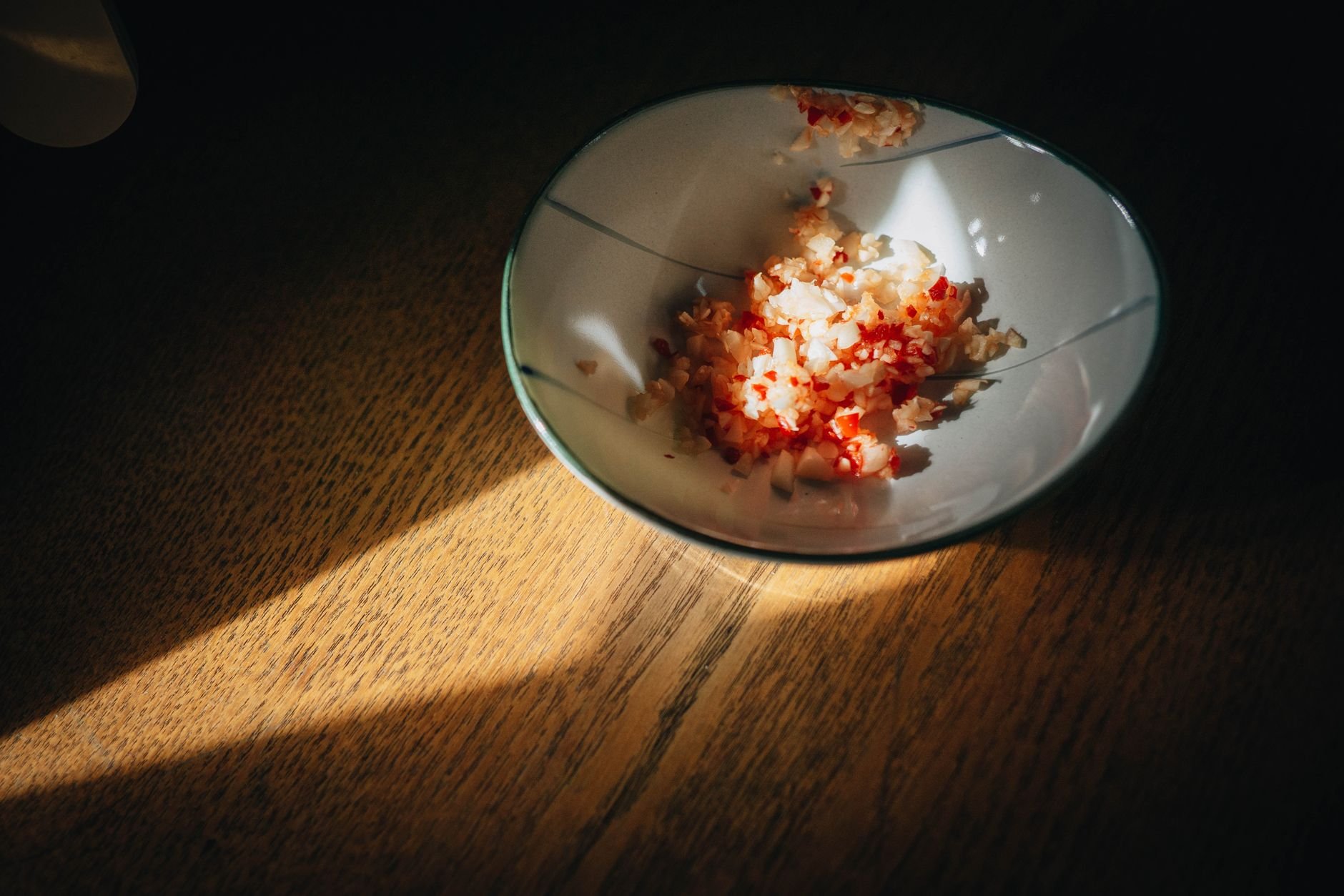 A bowl with fresh food ingredients in warm light on a wooden table.